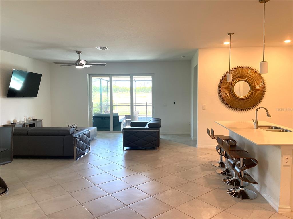 An open-concept living room and kitchen feature tile floors, a ceiling fan, and bar seating — 11141 PINOT DRIVE, VENICE, FL
