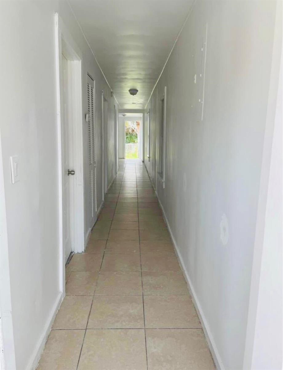 A long, narrow hallway features light-colored tile flooring and plain white walls — 706 7th Street, West Palm Beach FL 33401, WEST PALM BEACH, FL
