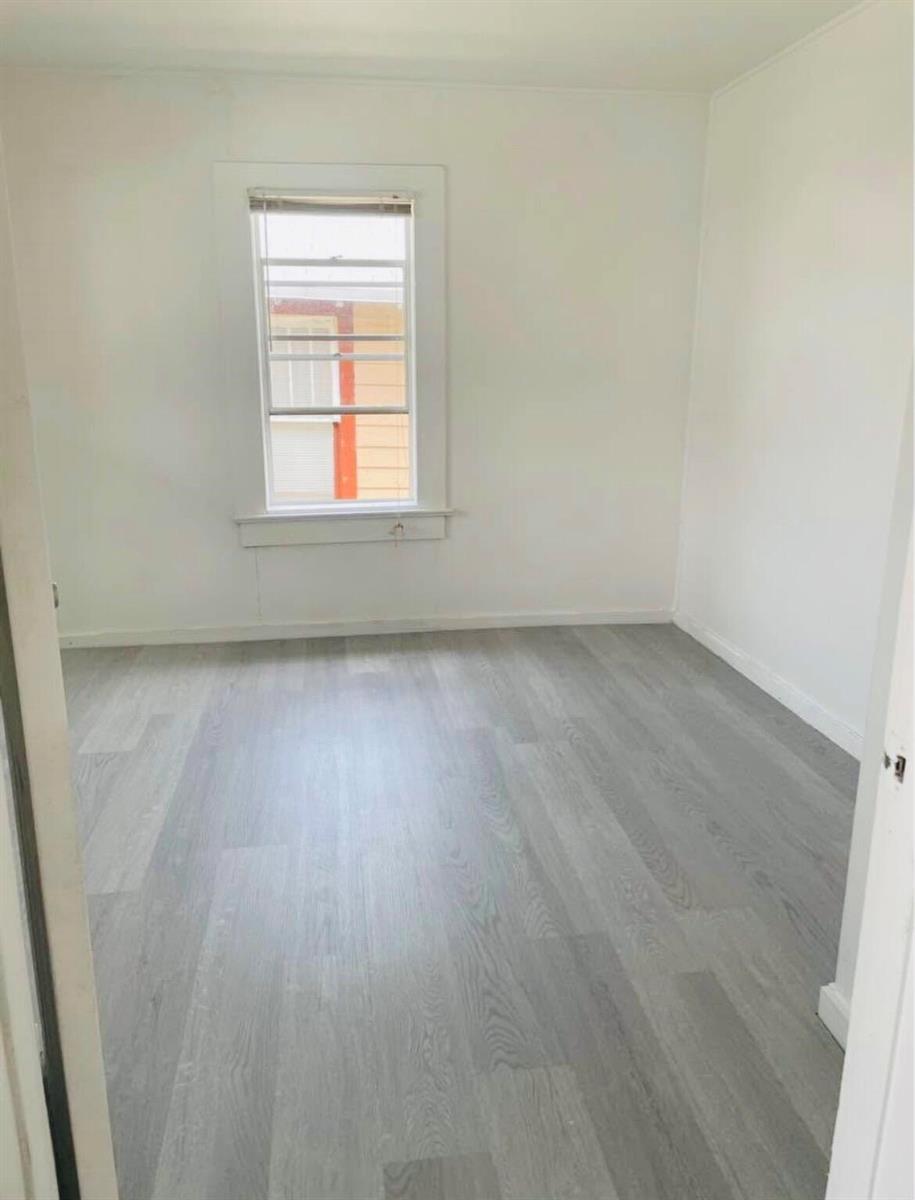 An empty room with white walls, gray wood-look flooring, and a single window — 706 7th Street, West Palm Beach FL 33401, WEST PALM BEACH, FL