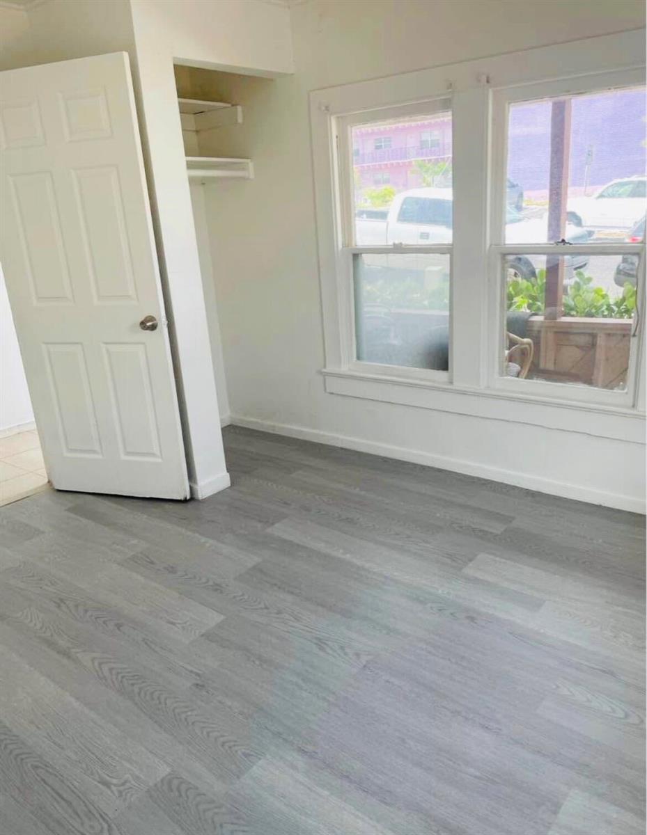 An empty room with gray wood-look flooring, a white door, and two windows — 706 7th Street, West Palm Beach FL 33401, WEST PALM BEACH, FL