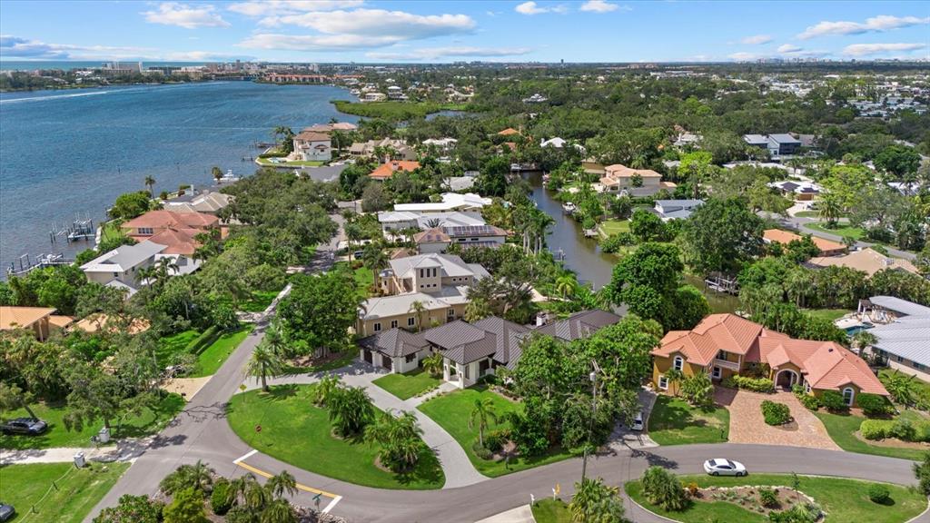 An aerial view shows waterfront homes with tiled roofs, lush landscaping, and a winding canal — 1707 CARIBBEAN DRIVE, SARASOTA, FL