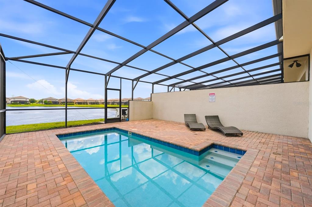 A screened-in patio features a rectangular swimming pool, brick pavers, and two lounge chairs — 8866 GENEVE COURT, KISSIMMEE, FL
