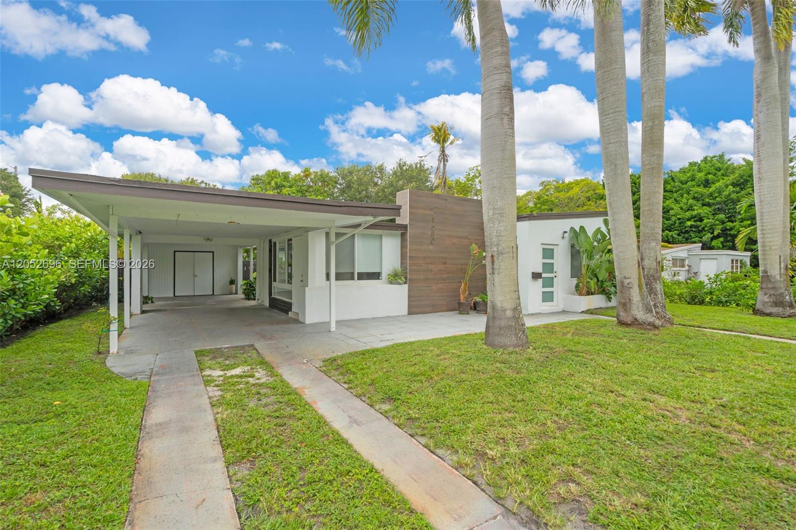 A single-story house features a carport, a wood-paneled facade, and tall palm trees — 1580 NE 139th St, North Miami FL 33161, NORTH MIAMI, FL