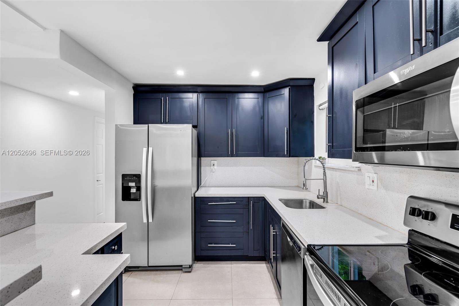 A kitchen features dark blue cabinets, stainless steel appliances, and white quartz countertops — 1580 NE 139th St, North Miami FL 33161, NORTH MIAMI, FL