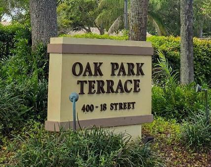 A tan monument sign with dark lettering stands in a garden with trees and shrubs — 400 18th Street # D, Vero Beach FL 32960, VERO BEACH, FL