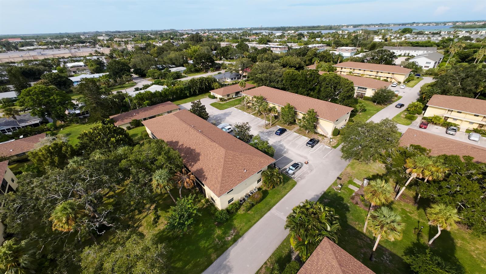 An aerial view shows several multi-story apartment buildings surrounded by trees and parking lots — 400 18th Street # D, Vero Beach FL 32960, VERO BEACH, FL