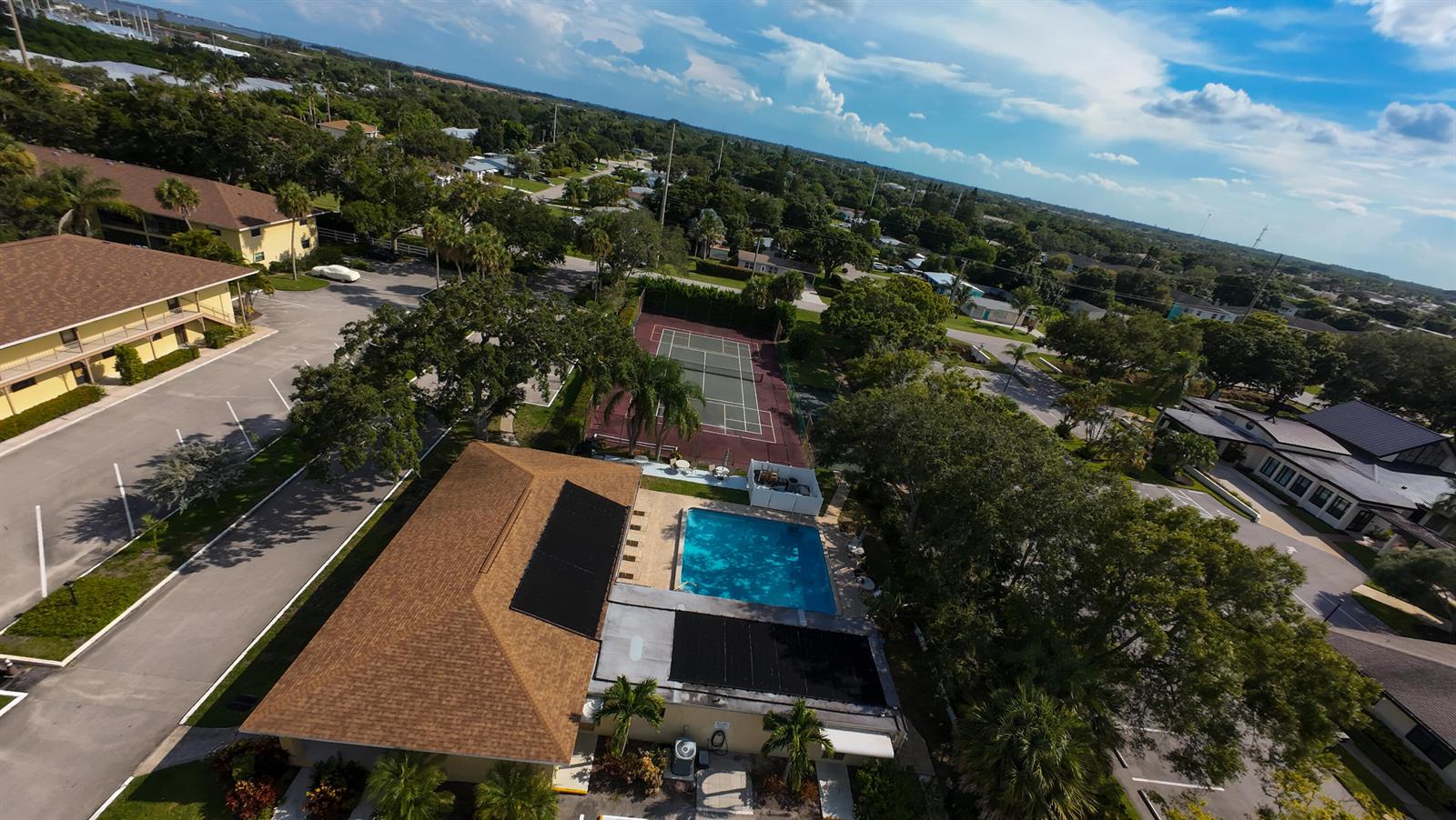 An aerial view shows a community pool, tennis court, and surrounding buildings with parking lots — 400 18th Street # D, Vero Beach FL 32960, VERO BEACH, FL