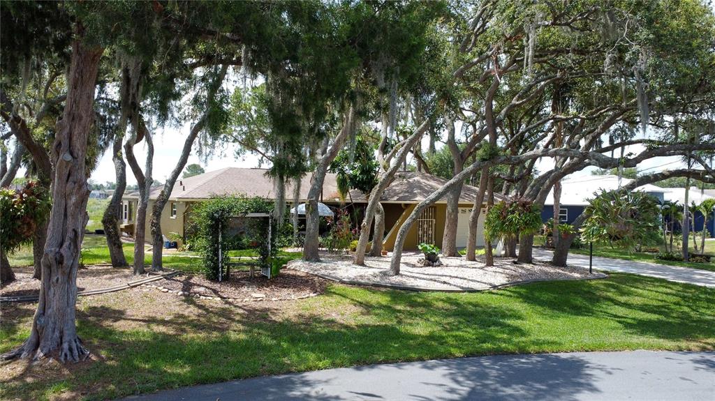 A single-story house with a tan exterior is surrounded by many large, moss-draped oak trees — 268 EASTPOINT COURT, SPRING HILL, FL