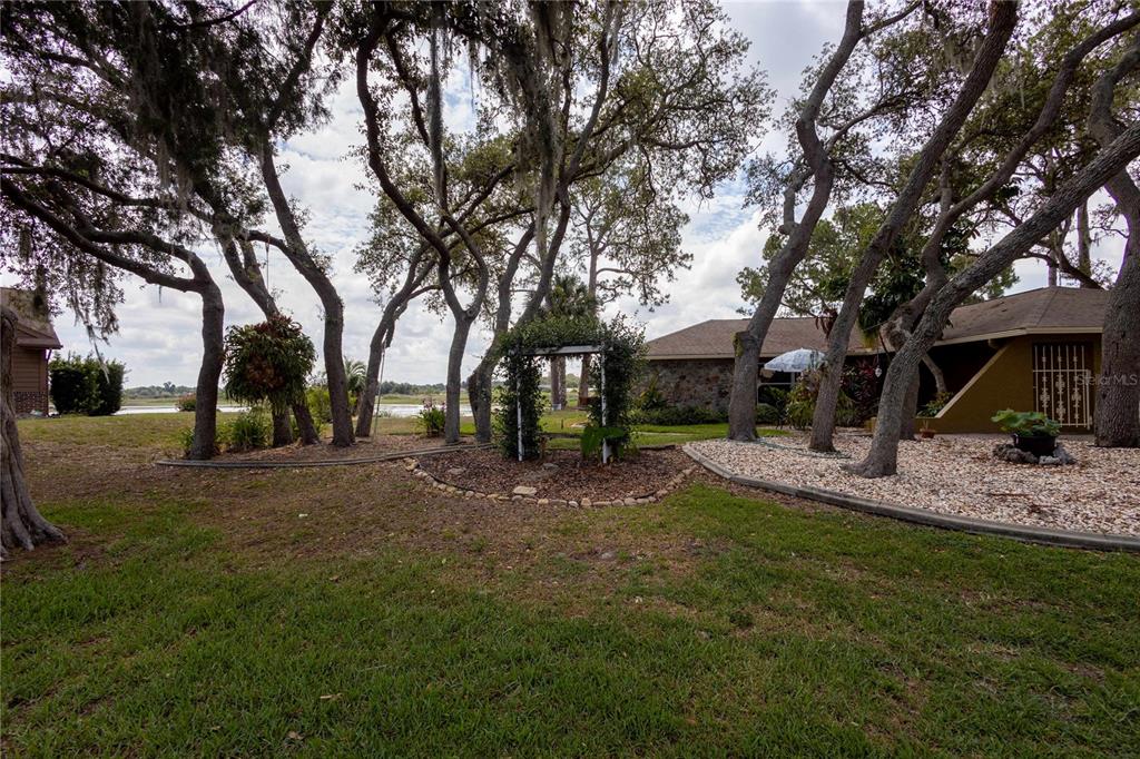 A backyard with mature trees, a garden arbor, and a view of the water — 268 EASTPOINT COURT, SPRING HILL, FL