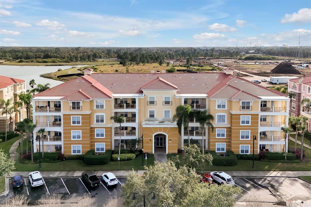 An exterior view of a multi-story apartment building with a tiled roof and parking lot — 5036 SHOREWAY LOOP UNIT 30105, ORLANDO, FL