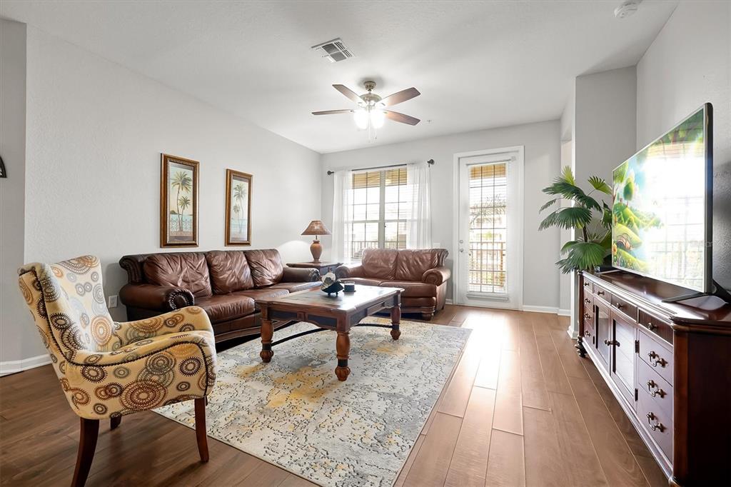 A living room features a leather sofa set, patterned armchair, area rug, and television console — 5036 SHOREWAY LOOP UNIT 30105, ORLANDO, FL