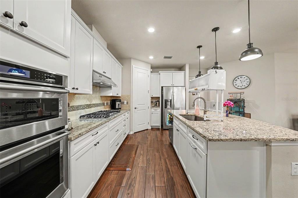A kitchen with white cabinets, granite countertops, stainless steel appliances, and a central island — 12890 PAYTON STREET, ODESSA, FL