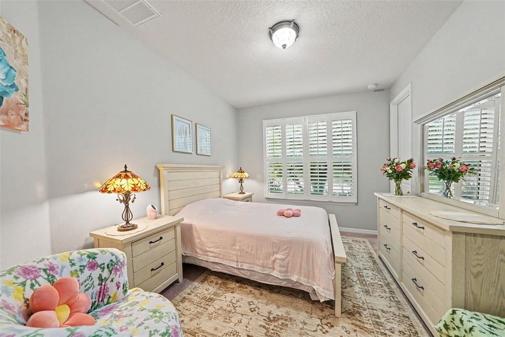 A bedroom features a bed with a light pink quilt, two nightstands, and a dresser — 12890 PAYTON STREET, ODESSA, FL