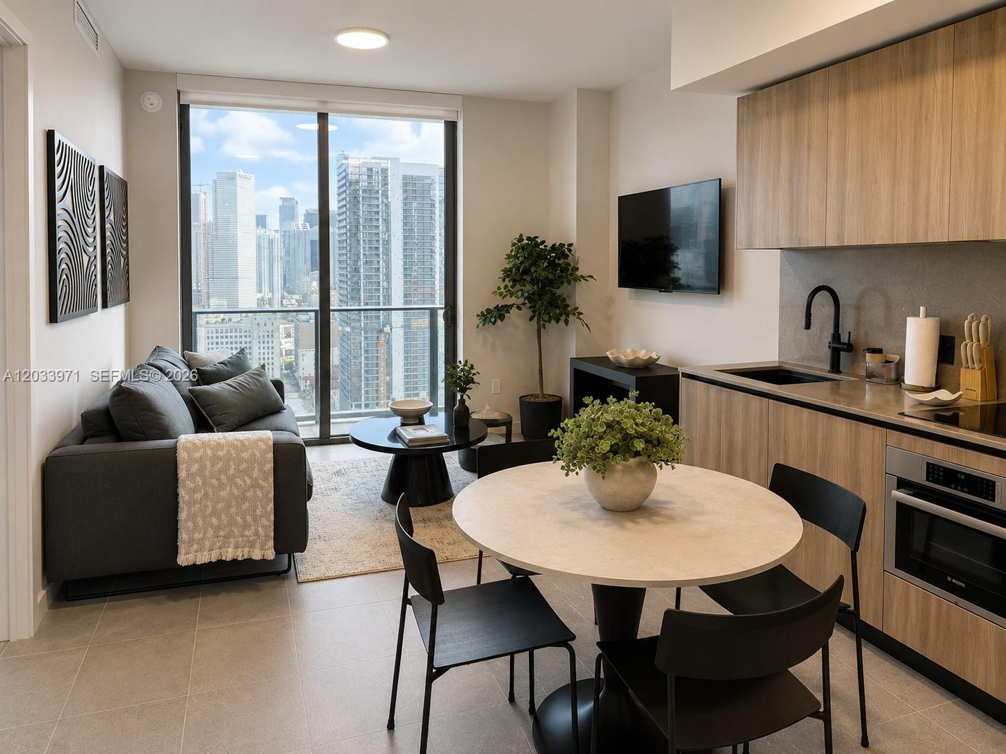 A modern apartment features a living area, dining table, and kitchen with city skyline views — 121 NE 5th St # 3002, Miami FL 33132, MIAMI, FL