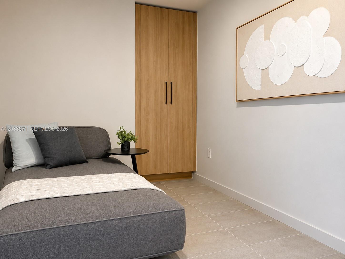 A gray daybed sits next to a wooden closet in a room with tiled floors — 121 NE 5th St # 3002, Miami FL 33132, MIAMI, FL