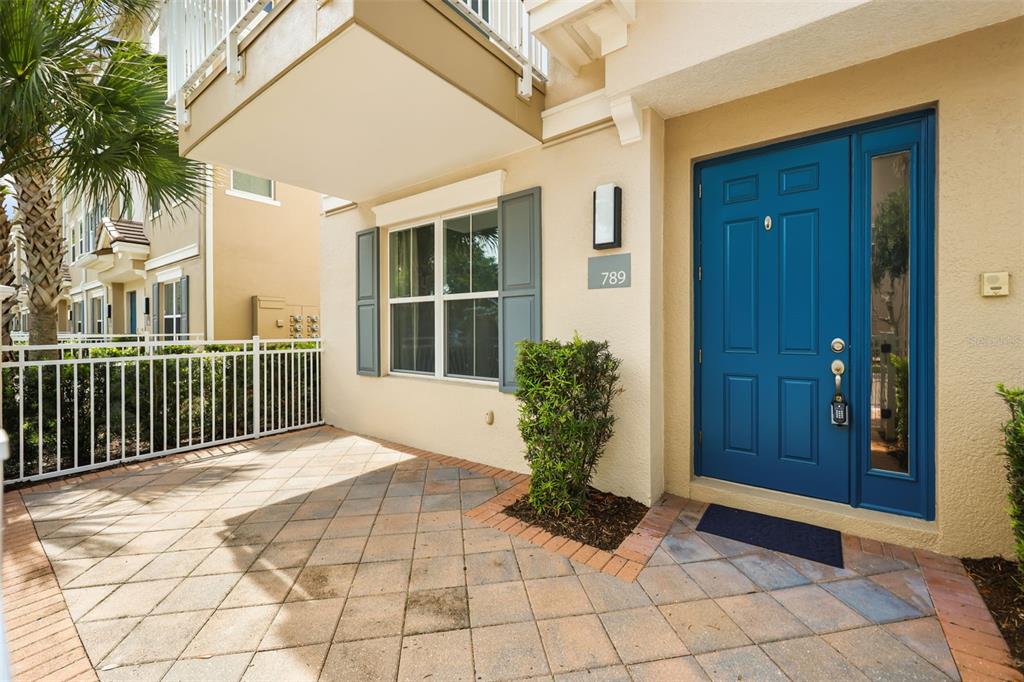 A blue front door with a sidelight sits beside a patio with stone pavers — 789 GREYBULL RUN, LAKE MARY, FL
