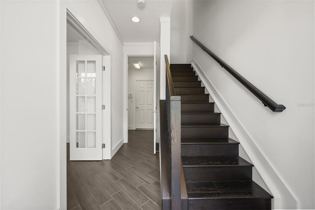 A staircase with dark wood treads and a black railing sits beside a hallway with tile flooring — 789 GREYBULL RUN, LAKE MARY, FL