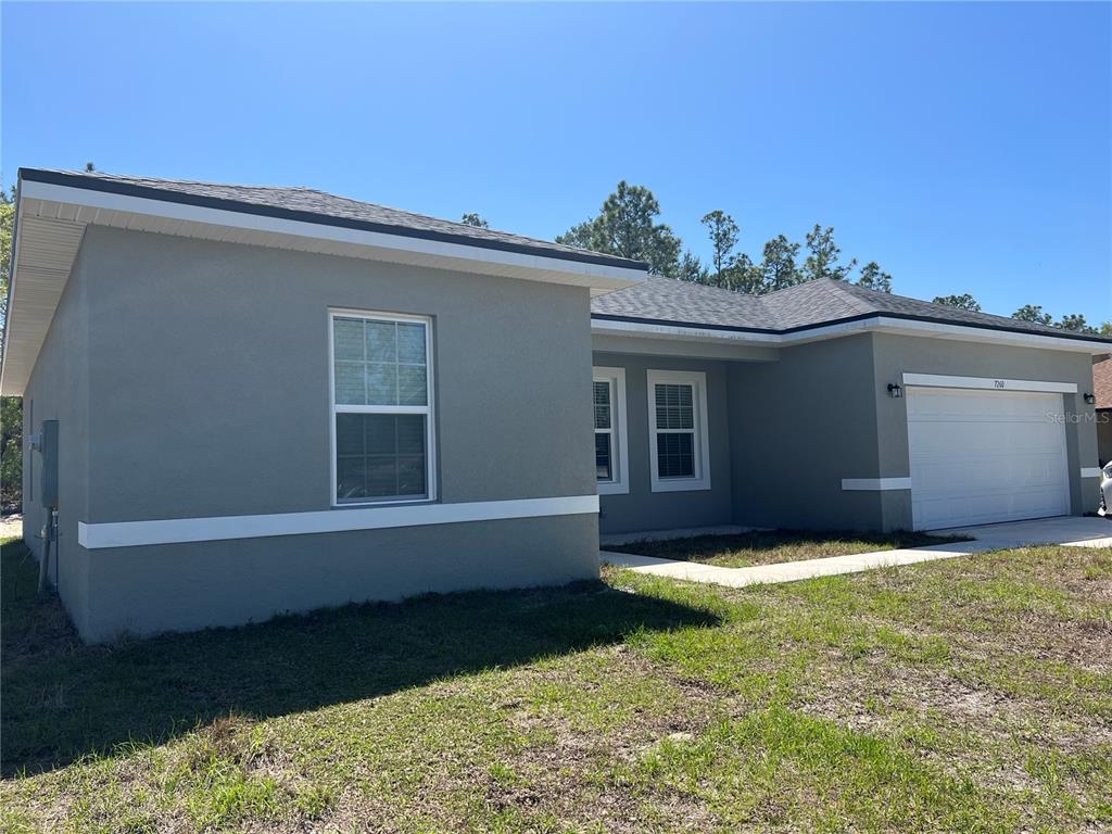 A single-story gray house with a white garage door and a concrete walkway — 7260 SW 132ND PLACE, OCALA, FL