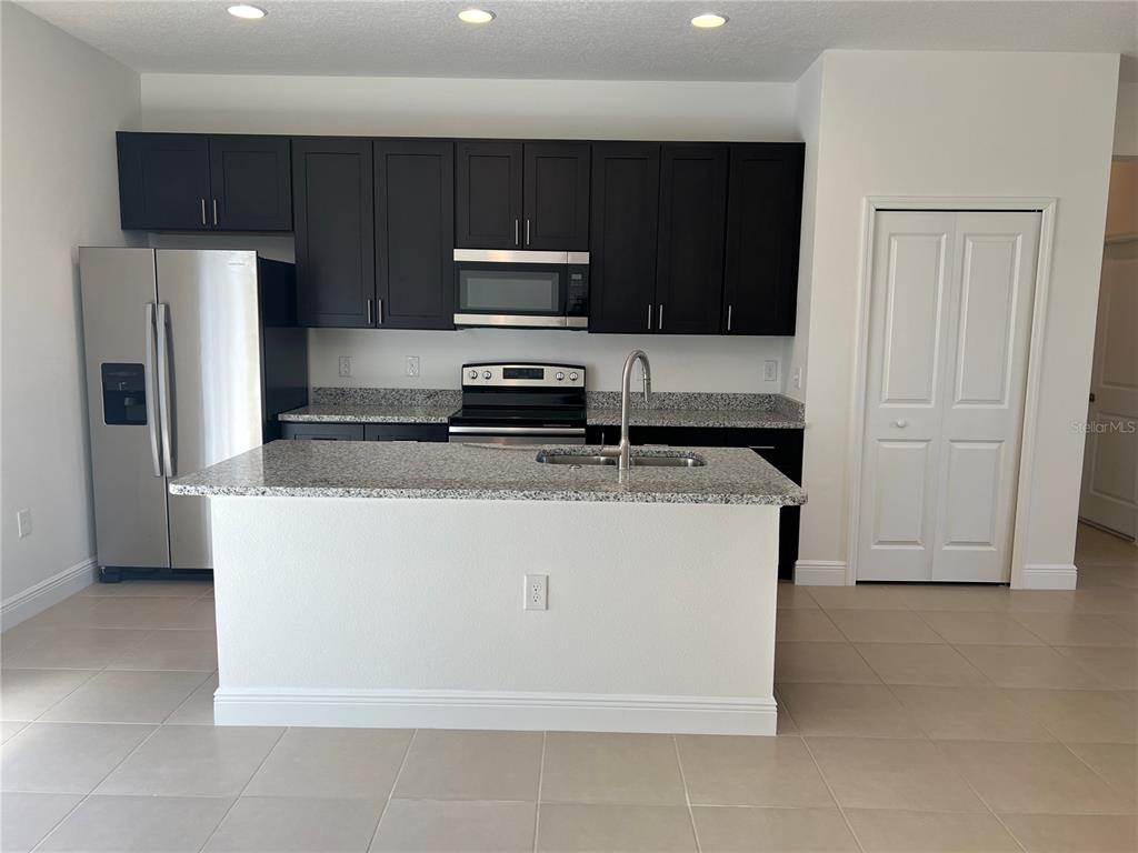 A kitchen features dark cabinets, stainless steel appliances, granite countertops, and a central island — 7260 SW 132ND PLACE, OCALA, FL