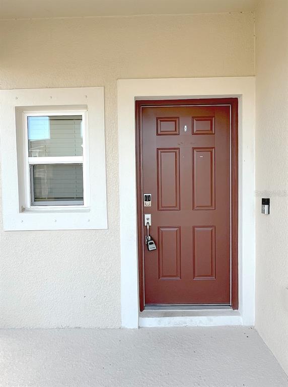 A brown front door with a lockbox and a window are set in a beige wall — 11832 GLENSIDE TERRACE, PALMETTO, FL