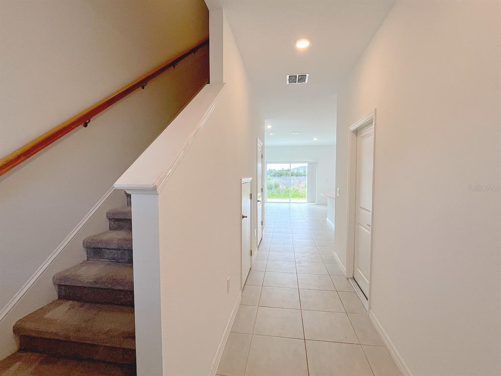 A carpeted staircase leads upstairs next to a tiled hallway with a view of outdoors — 11832 GLENSIDE TERRACE, PALMETTO, FL
