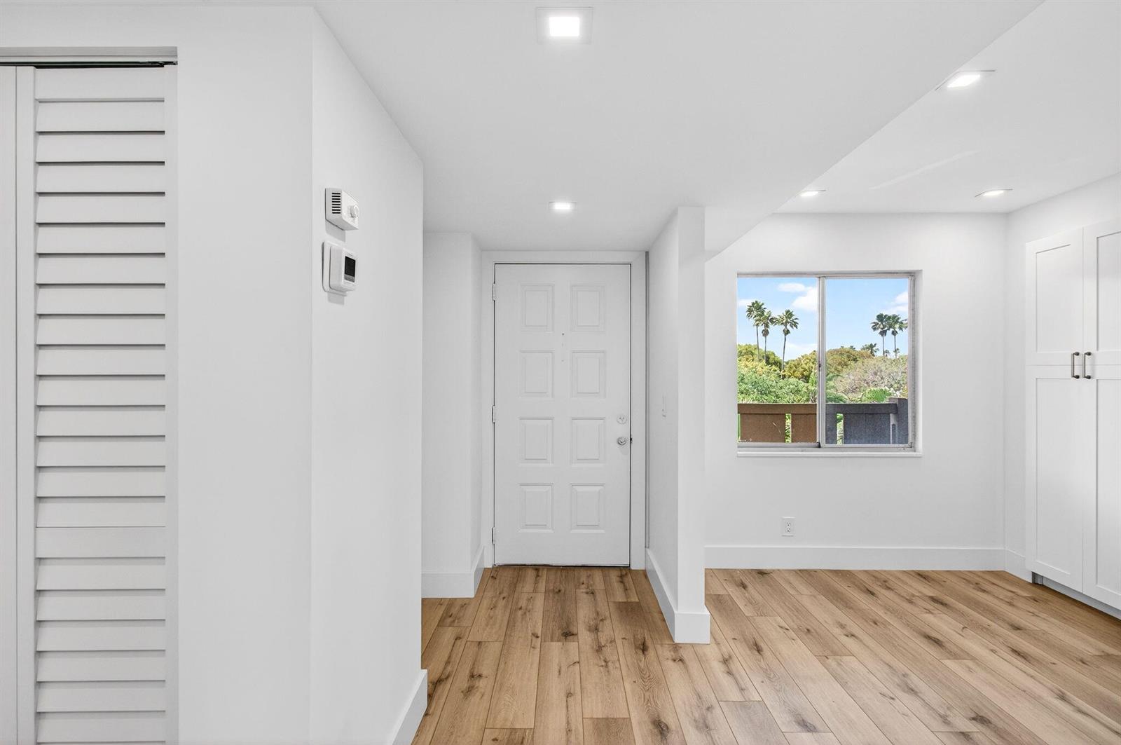 An interior view of a room with white walls, wood-look flooring, and a white door — 14360 Strathmore Lane # 406, Delray Beach FL 33446, DELRAY BEACH, FL