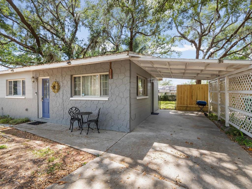 A gray house with a blue door, a concrete patio, and an attached carport — 8512 N 29TH STREET, TAMPA, FL