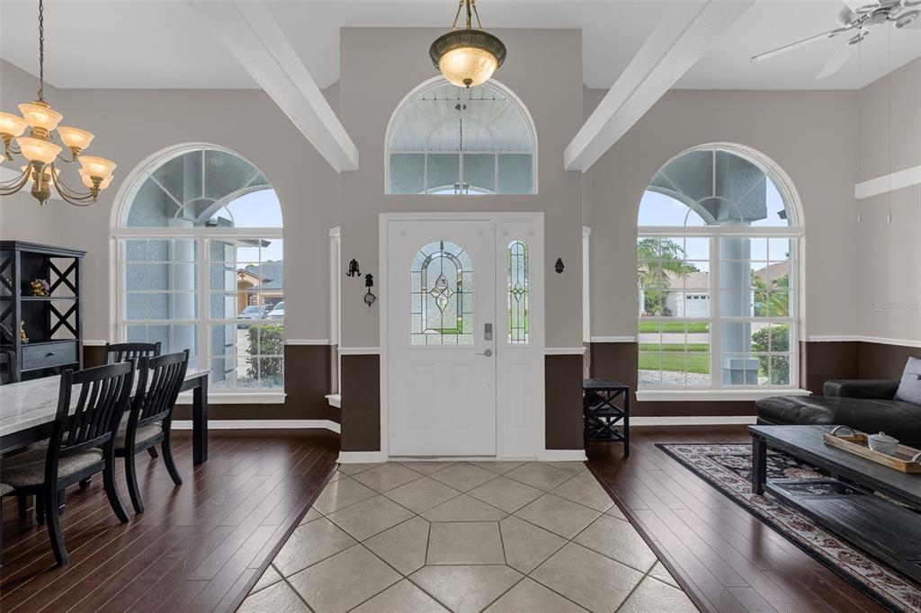 A bright foyer features tile flooring, a white front door, and arched windows — 1934 FAIRWAY LOOP, KISSIMMEE, FL