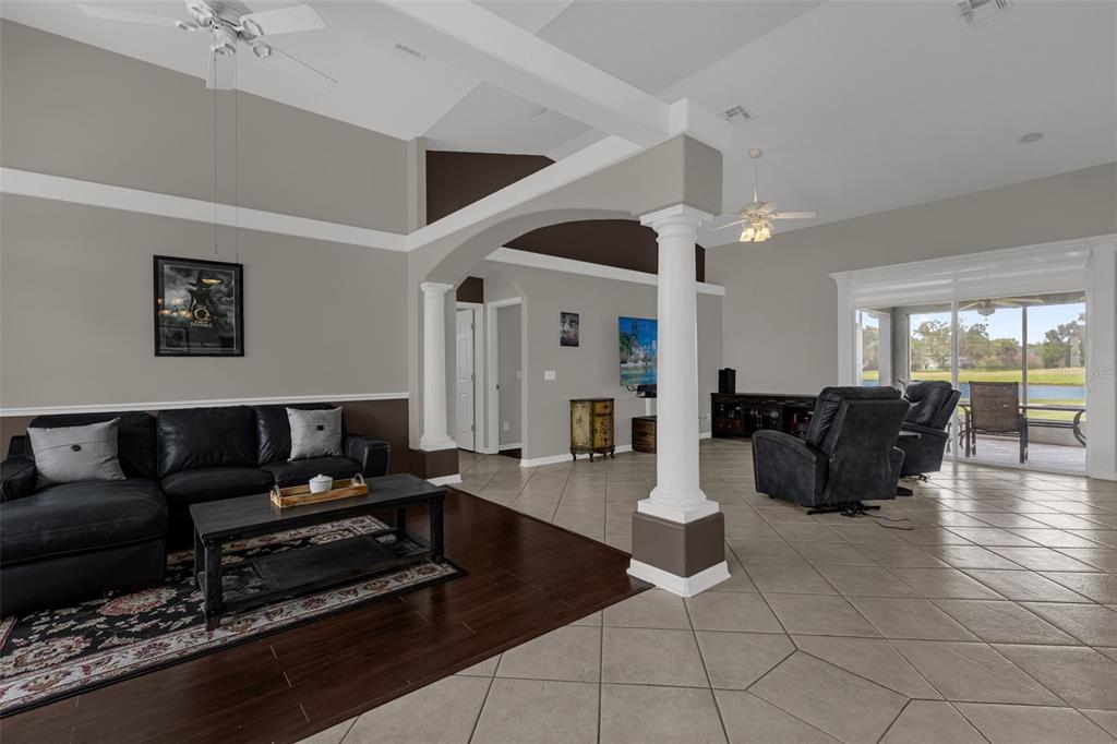 A spacious living room features a dark wood floor area, tiled flooring, and an arched column — 1934 FAIRWAY LOOP, KISSIMMEE, FL