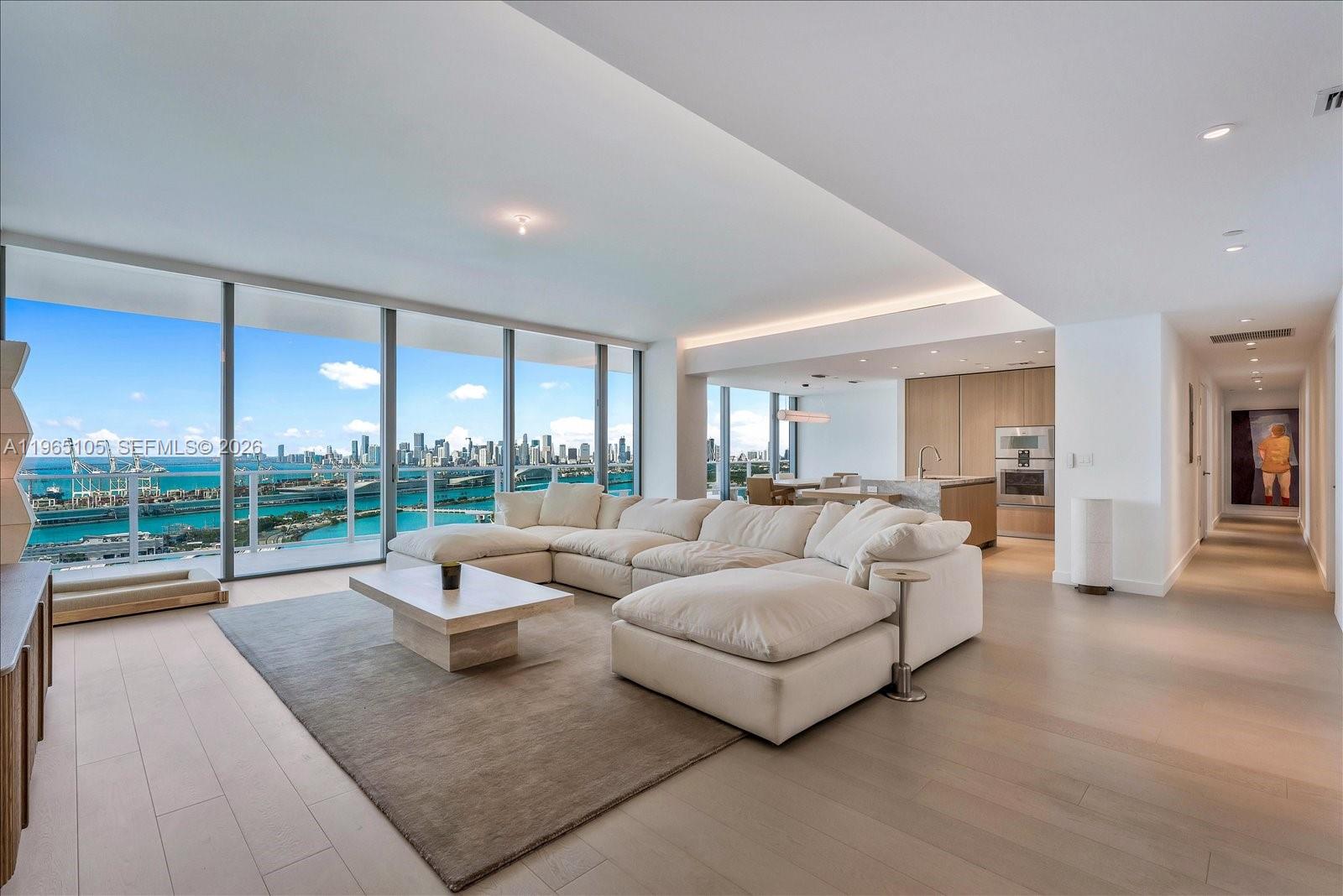 A modern living room features a large white sectional sofa, light wood floors, and floor-to-ceiling windows — 501 West Ave # 3102, Miami Beach FL 33139, MIAMI BEACH, FL