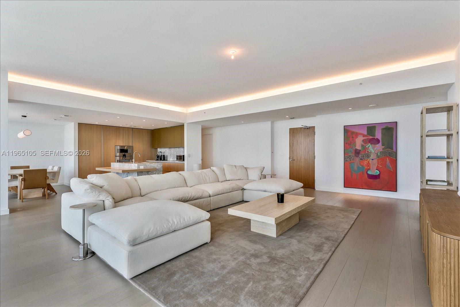 A modern living room features a large white sectional sofa, a wooden coffee table, and artwork — 501 West Ave # 3102, Miami Beach FL 33139, MIAMI BEACH, FL
