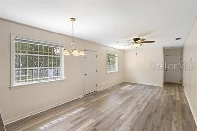 A bright, empty room features light-colored wood-look flooring, a ceiling fan, and a chandelier — 420 N FAIRVIEW AVENUE, DELAND, FL