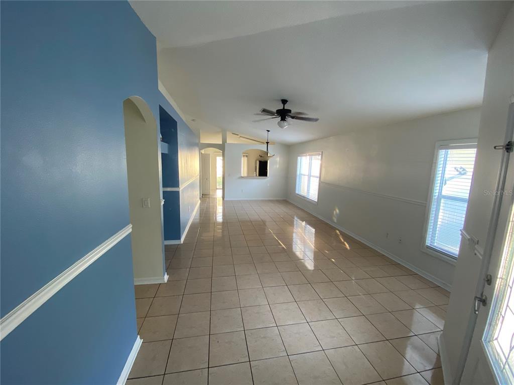 A long, tiled living area features blue accent walls, a ceiling fan, and large windows — 8530 QUARTER HORSE DRIVE, RIVERVIEW, FL