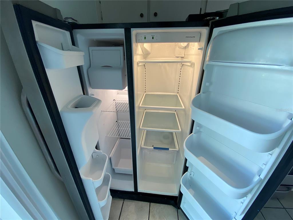 An open, white Frigidaire side-by-side refrigerator with adjustable shelves and door bins — 8530 QUARTER HORSE DRIVE, RIVERVIEW, FL