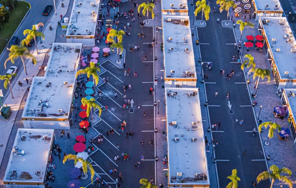 An aerial view shows a commercial outdoor plaza with multiple buildings, palm trees, and pedestrians — 5888 GRAND ORO LANE UNIT 112, WESLEY CHAPEL, FL