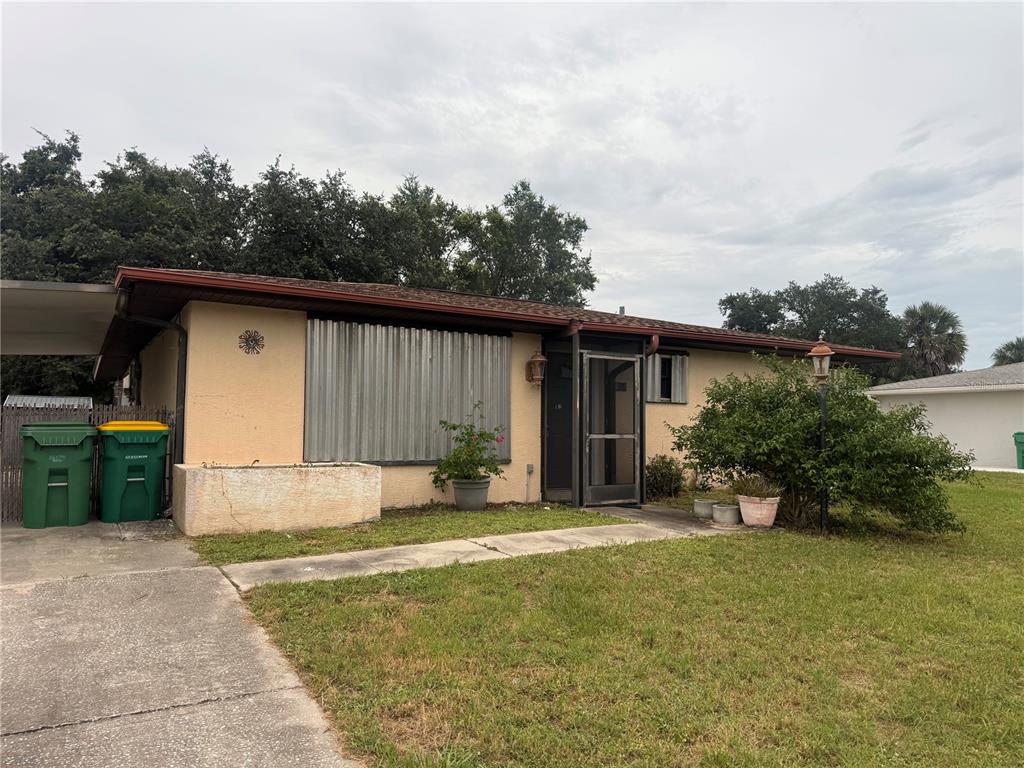 A single-story house with a concrete driveway, metal storm shutters, and a front lawn — 23014 MCNULTY AVENUE, PORT CHARLOTTE, FL