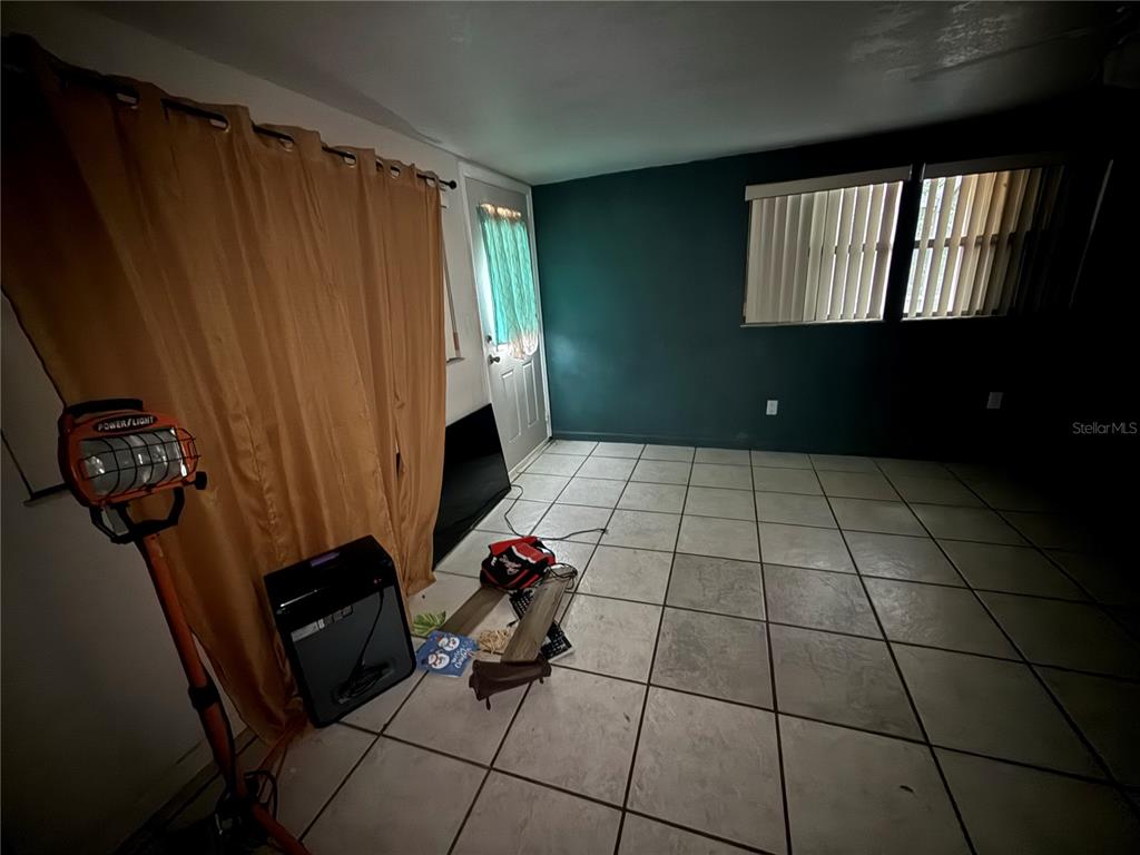 A room with tiled floors, a dark accent wall, and a door with curtains — 23014 MCNULTY AVENUE, PORT CHARLOTTE, FL