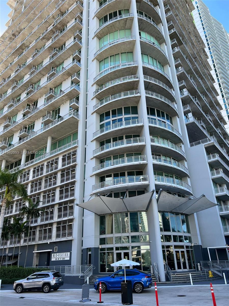 The exterior of a modern high-rise apartment building features curved balconies and a valet entrance — 690 SW 1st Ct # 1506, Miami FL 33130, MIAMI, FL
