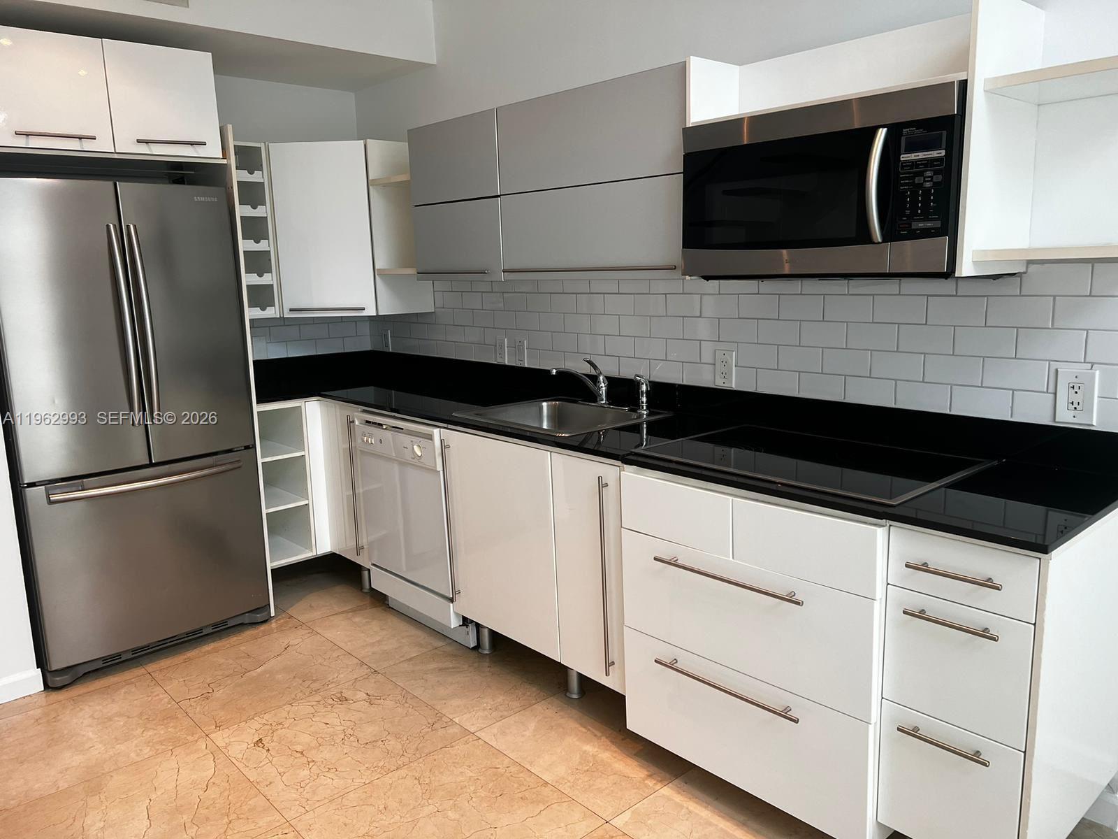 A modern kitchen features white cabinets, stainless steel appliances, and black countertops — 690 SW 1st Ct # 1506, Miami FL 33130, MIAMI, FL