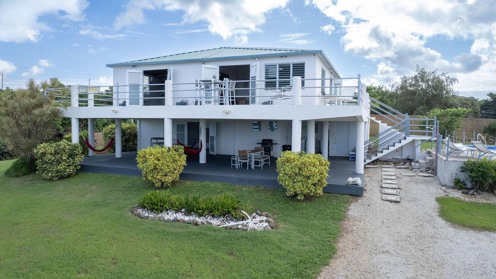 An elevated house with a large deck, outdoor seating, and a staircase leading to the yard — 590-A CALLE 16, COMM VILLA BORINQUEN, VIEQUES, PR