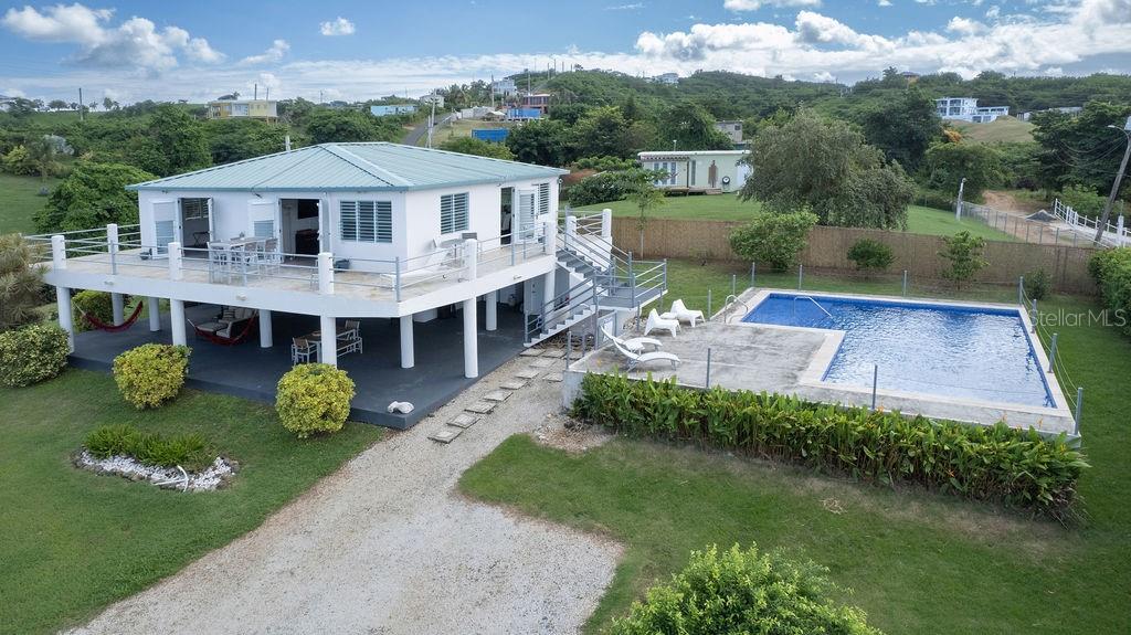 An elevated white house with a metal roof, a wrap-around deck, and an outdoor pool — 590-A CALLE 16, COMM VILLA BORINQUEN, VIEQUES, PR