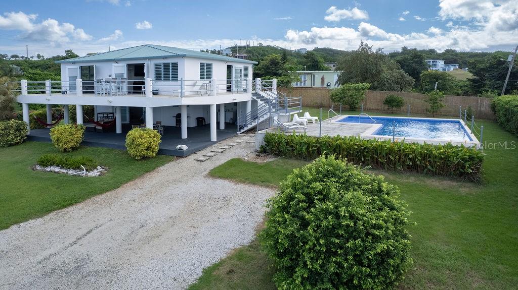 An elevated white house with a wrap-around deck, swimming pool, and gravel driveway — 590-A CALLE 16, COMM VILLA BORINQUEN, VIEQUES, PR