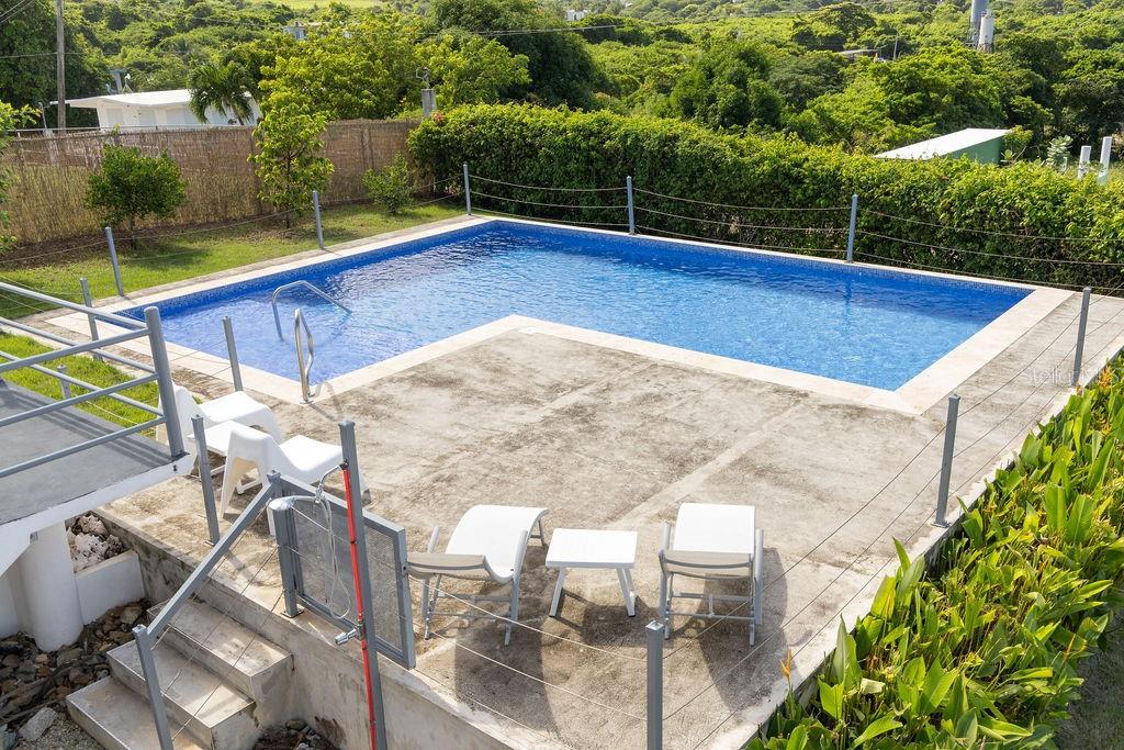 An elevated outdoor swimming pool with a concrete patio, lounge chairs, and surrounding greenery — 590-A CALLE 16, COMM VILLA BORINQUEN, VIEQUES, PR