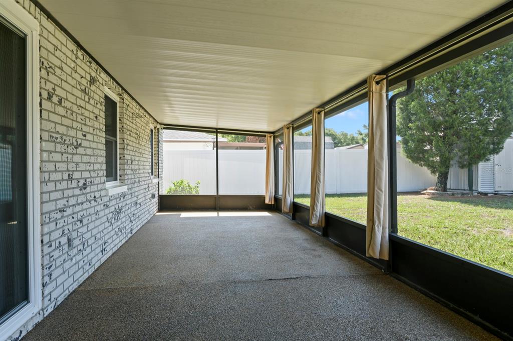 A covered screened-in patio with a concrete floor and white brick exterior wall — 11403 FILLMORE AVENUE, SEFFNER, FL