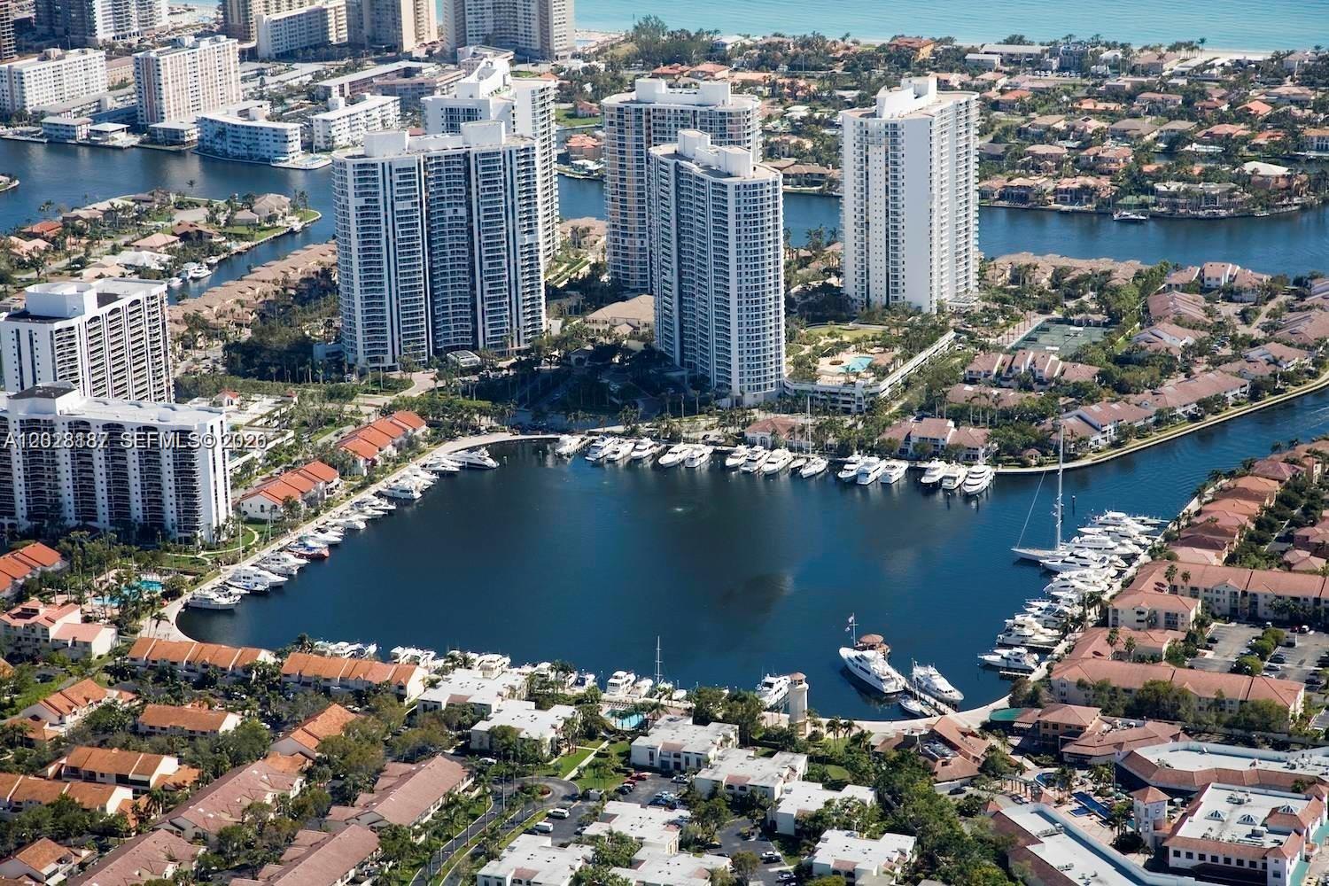 An aerial view of a marina surrounded by residential high-rise buildings and suburban homes — AVENTURA, FL