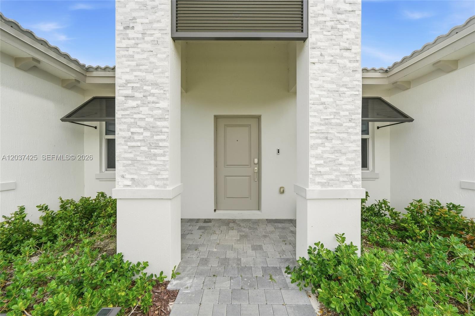 The exterior entrance features a stone-clad pillar, a beige door, and gray paver flooring — 13249 SW 189th Ter, Miami FL 33177, MIAMI, FL