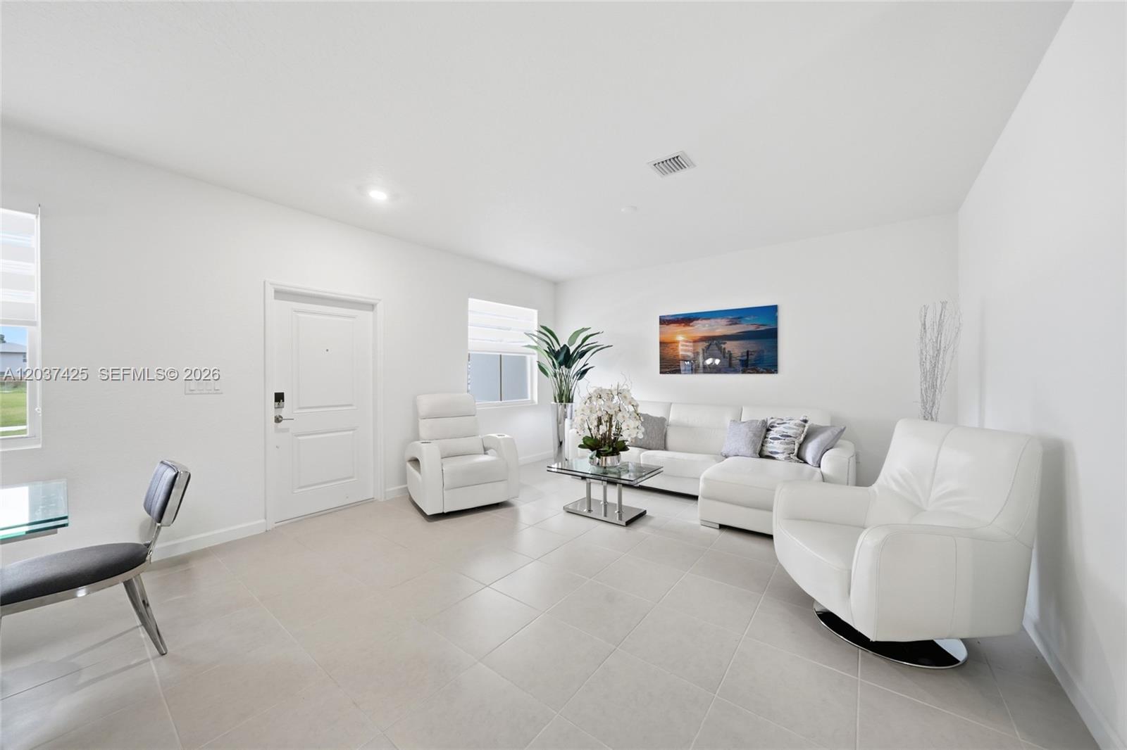 A bright living room features white leather furniture, tile flooring, and a sunset wall art piece — 13249 SW 189th Ter, Miami FL 33177, MIAMI, FL