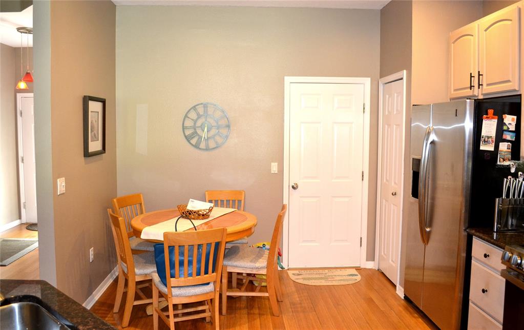 A dining area features a round wooden table with four chairs and a wall clock — 11158 KAPOK GRAND CIRCLE, MADEIRA BEACH, FL