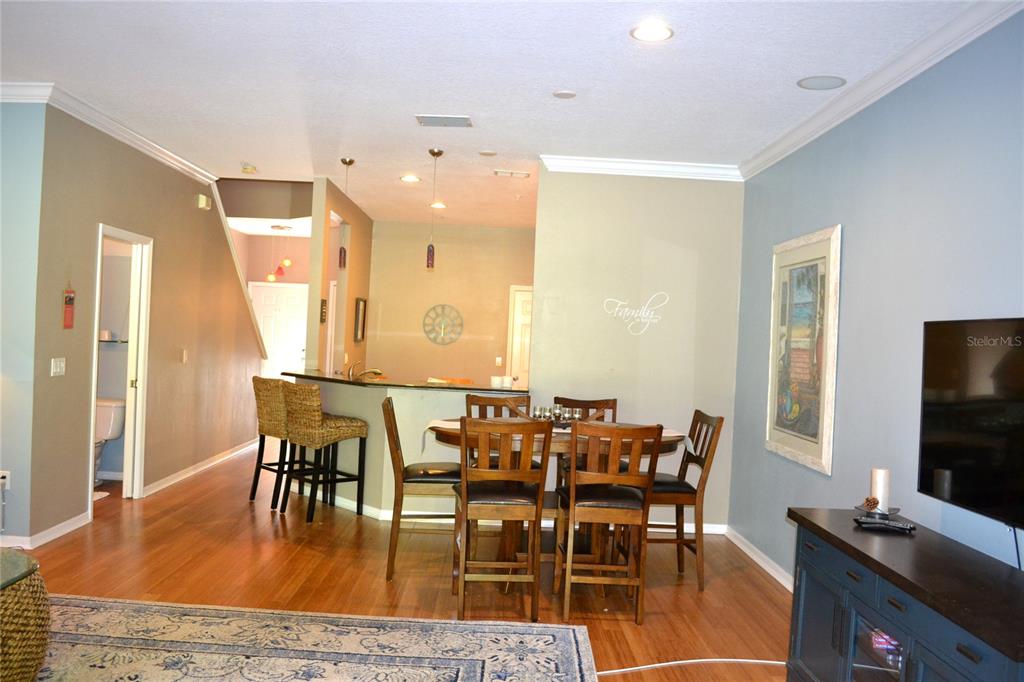 A dining area with a wooden table and chairs sits adjacent to a kitchen counter — 11158 KAPOK GRAND CIRCLE, MADEIRA BEACH, FL