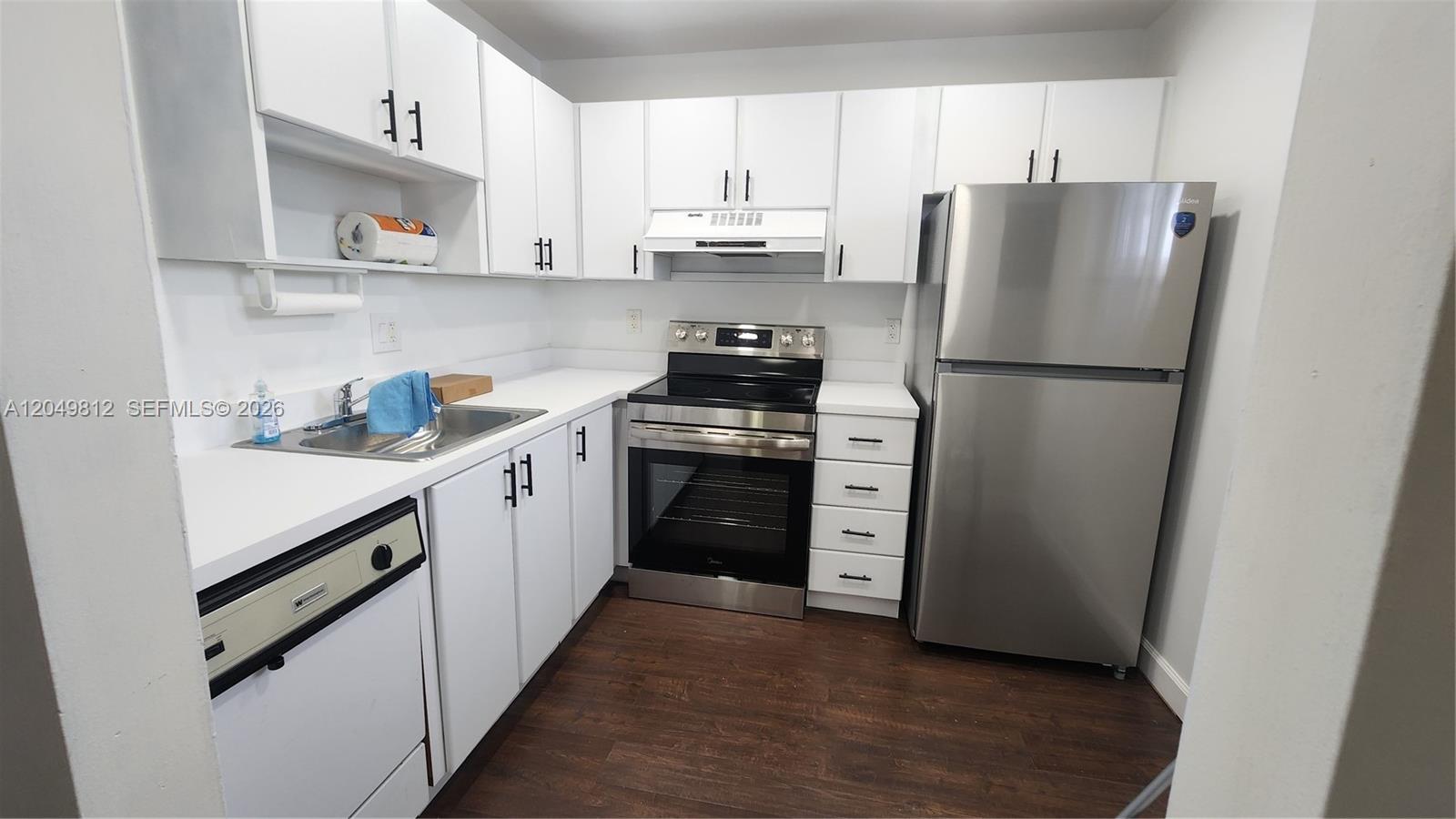 A kitchen features white cabinets, stainless steel appliances, and dark wood-look flooring — 7541 NW 16th St # 1507, Plantation FL 33313, PLANTATION, FL
